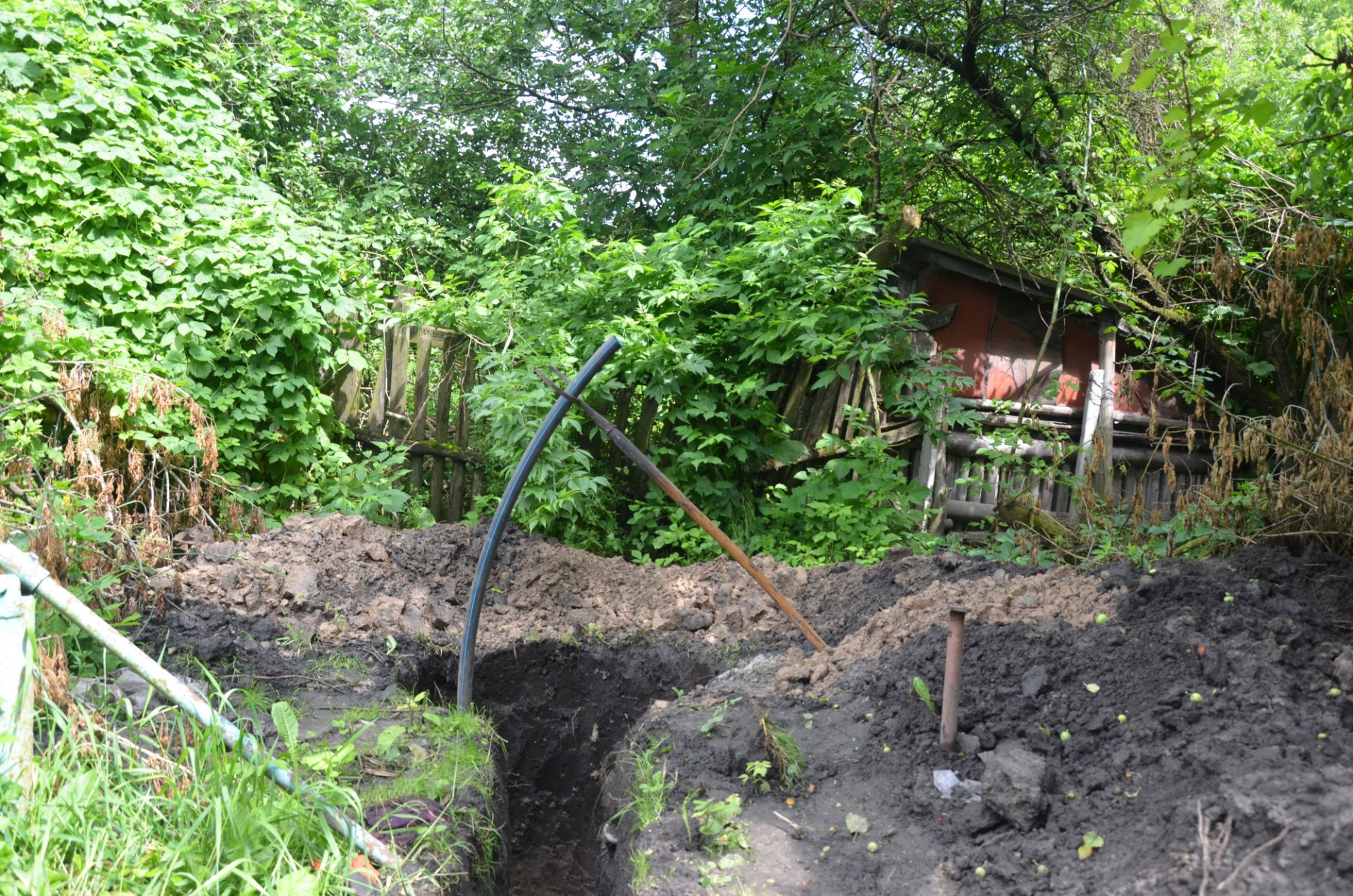 За хатою рясно буяє кропива, перед будинком – яма-траншея, це нещодавно викопали свердловину